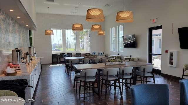 dining area with dark wood-type flooring, a wealth of natural light, and a high ceiling