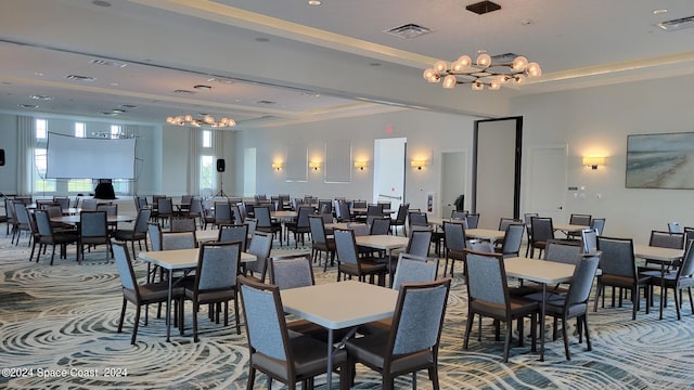 dining room featuring a tray ceiling, an inviting chandelier, and carpet floors