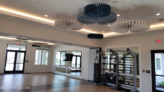 exercise room featuring baseboards, a raised ceiling, visible vents, and recessed lighting