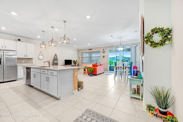 kitchen featuring a center island with sink, hanging light fixtures, stainless steel appliances, ornamental molding, and white cabinets