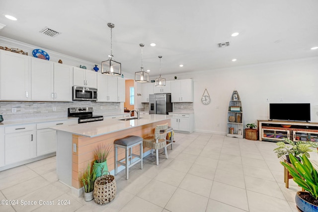 kitchen featuring pendant lighting, an island with sink, stainless steel appliances, sink, and white cabinets