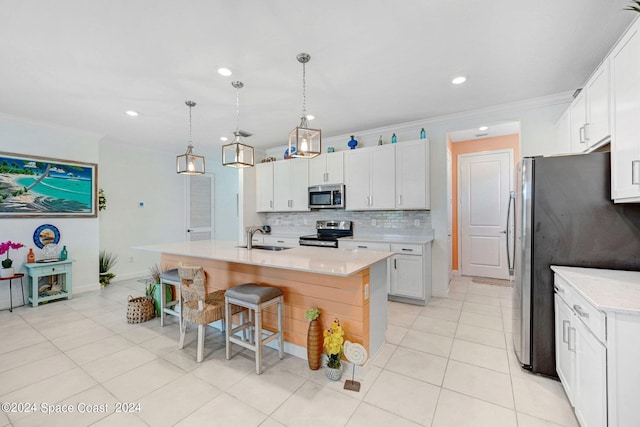 kitchen with a center island with sink, appliances with stainless steel finishes, hanging light fixtures, sink, and white cabinets