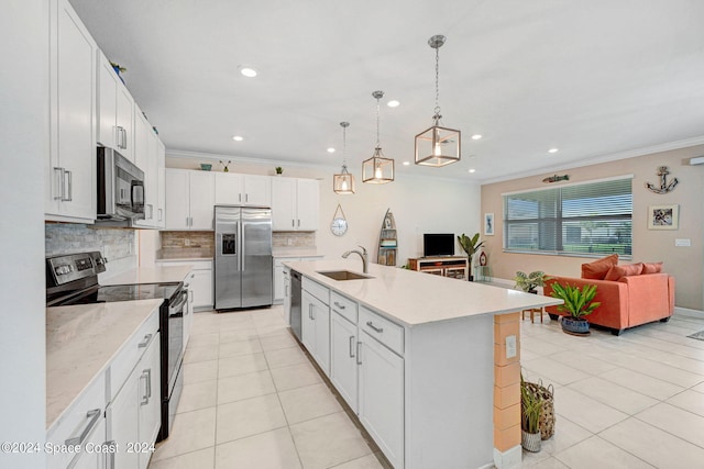 kitchen featuring decorative light fixtures, appliances with stainless steel finishes, a kitchen island with sink, sink, and white cabinetry