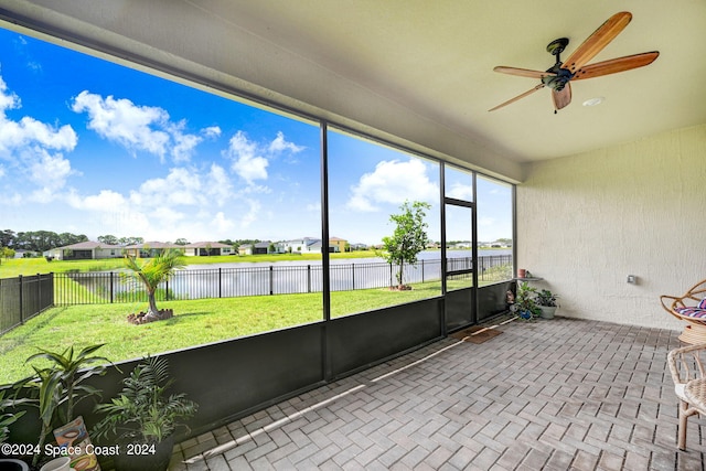 unfurnished sunroom with a ceiling fan and a water view