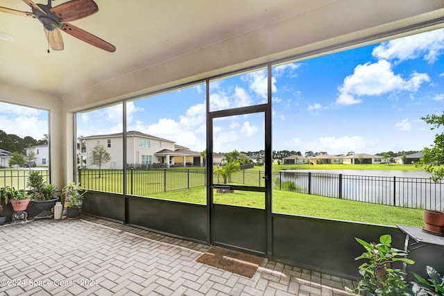 unfurnished sunroom with a water view and ceiling fan