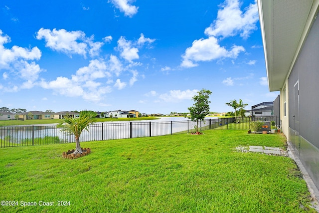 view of yard with a lanai, a residential view, a fenced backyard, and a water view