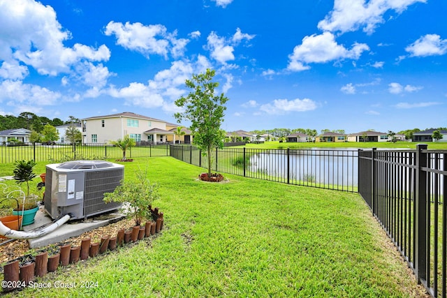 view of yard featuring a fenced backyard, central air condition unit, a residential view, and a water view