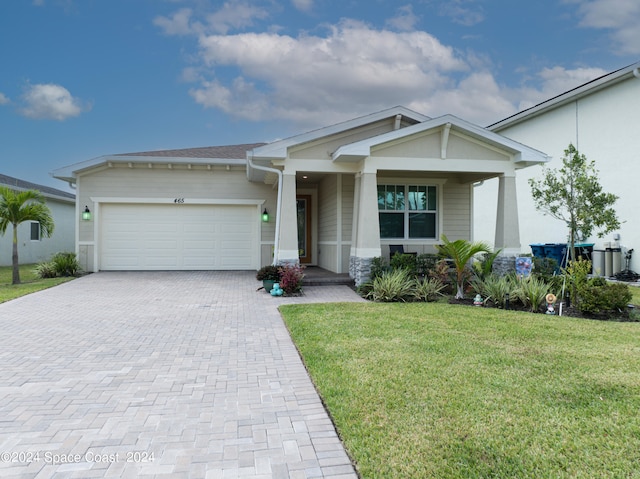 craftsman inspired home with a front yard, decorative driveway, and an attached garage