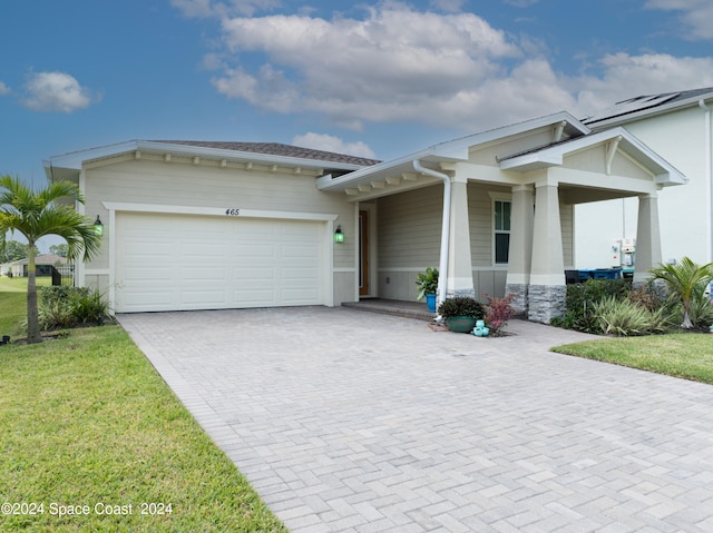 view of front of home with decorative driveway, a front lawn, and an attached garage