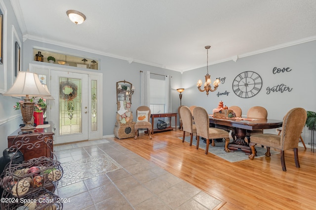 dining room with a textured ceiling, ornamental molding, light hardwood / wood-style flooring, and a notable chandelier