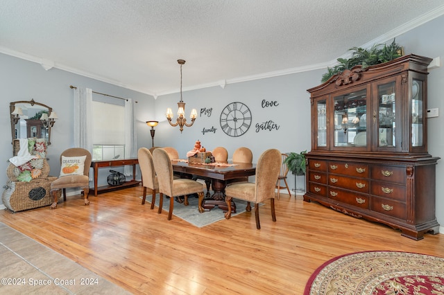 dining area with light wood-type flooring, crown molding, a textured ceiling, and a chandelier