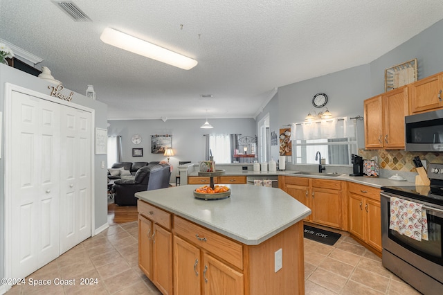 kitchen featuring light tile patterned floors, sink, tasteful backsplash, stainless steel appliances, and a center island