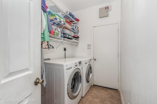 clothes washing area featuring washing machine and clothes dryer, a textured ceiling, and light tile patterned floors