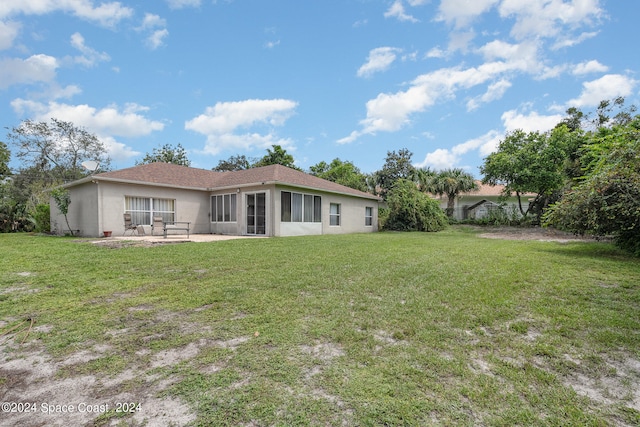 back of property with a sunroom, a lawn, and a patio