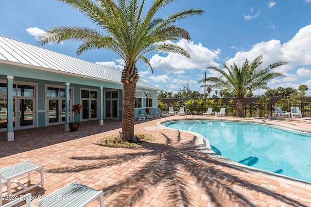 community pool featuring fence, a patio area, and french doors