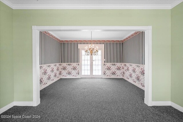 empty room with dark carpet, a chandelier, and ornamental molding