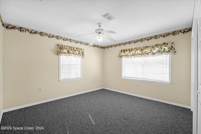 carpeted empty room with ceiling fan and plenty of natural light