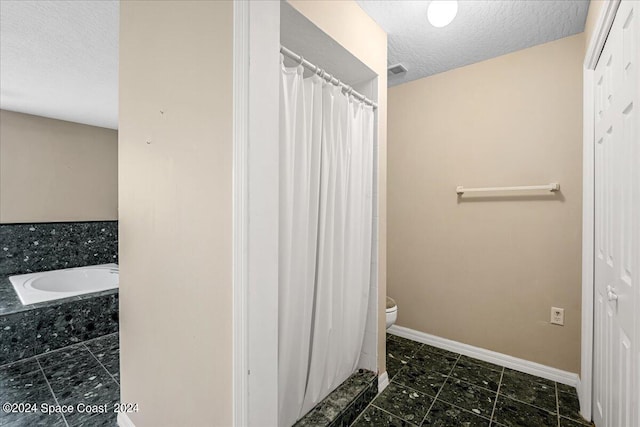 bathroom with curtained shower, toilet, and a textured ceiling