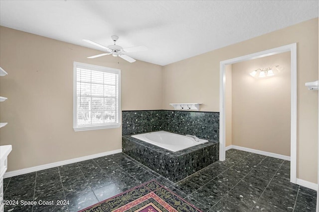 bathroom featuring a textured ceiling, ceiling fan, and a relaxing tiled tub