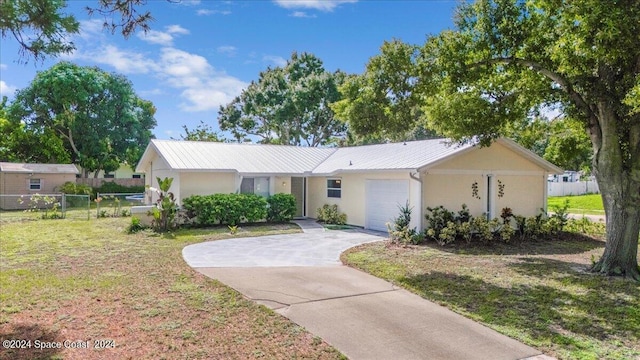 ranch-style house with stucco siding, fence, concrete driveway, an attached garage, and metal roof