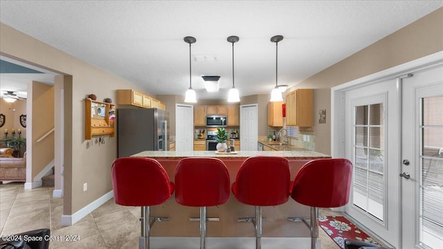 kitchen featuring decorative light fixtures, stainless steel appliances, kitchen peninsula, ceiling fan, and a breakfast bar