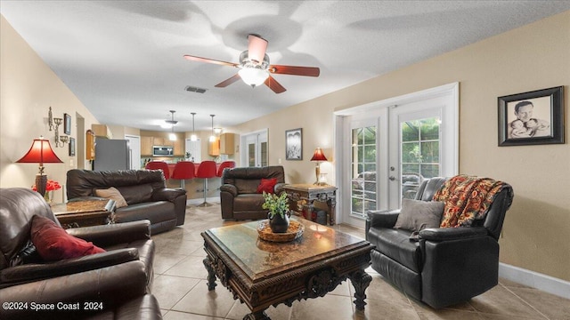 tiled living room featuring french doors, a textured ceiling, and ceiling fan