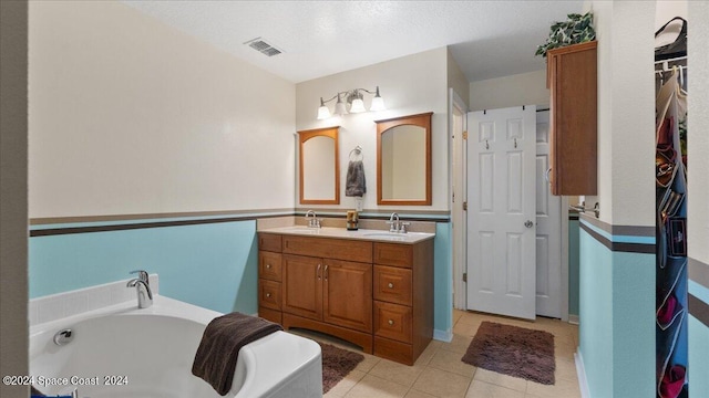 bathroom featuring a textured ceiling, vanity, a bath, and tile patterned floors