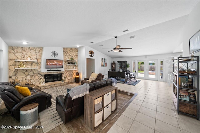 living room featuring a fireplace, a textured ceiling, light tile patterned floors, ceiling fan, and lofted ceiling