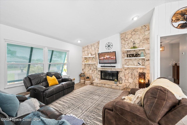 living room featuring plenty of natural light, vaulted ceiling, and a stone fireplace