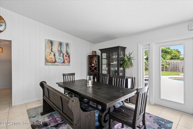 dining area featuring a textured ceiling, light tile patterned floors, and lofted ceiling