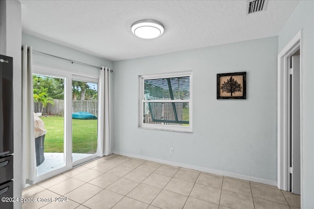 unfurnished room with a textured ceiling and light tile patterned flooring