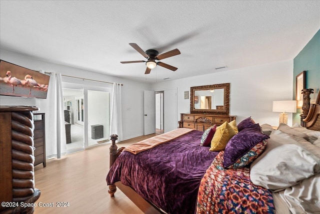 bedroom with light wood-type flooring, ceiling fan, and a textured ceiling