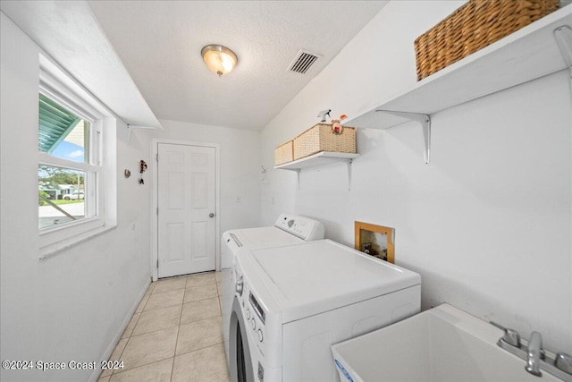 washroom featuring light tile patterned floors, sink, a textured ceiling, and separate washer and dryer