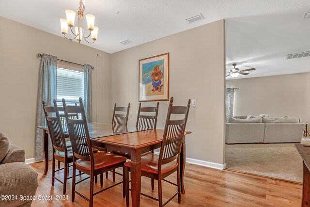 dining room with ceiling fan with notable chandelier and light hardwood / wood-style flooring