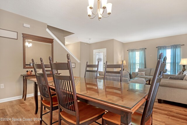 dining room with light hardwood / wood-style floors and a notable chandelier