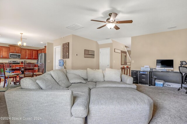 living room with ceiling fan with notable chandelier and carpet floors