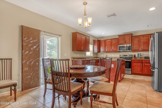 kitchen featuring pendant lighting, a notable chandelier, sink, appliances with stainless steel finishes, and light tile patterned flooring