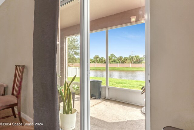 doorway featuring light carpet and a water view