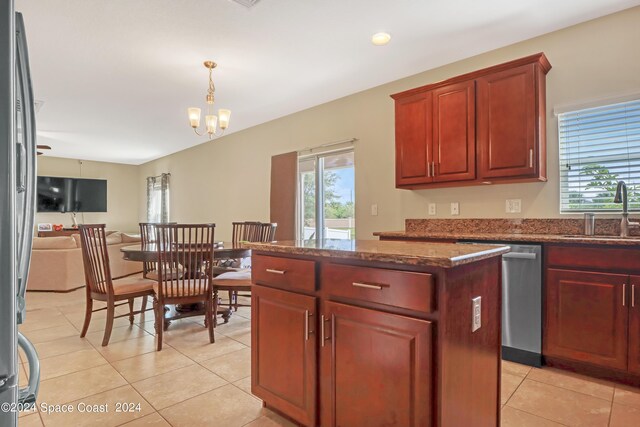 kitchen featuring a kitchen island, decorative light fixtures, a notable chandelier, appliances with stainless steel finishes, and sink