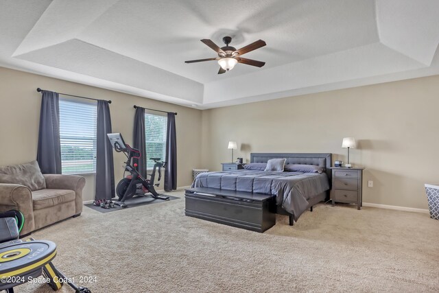 carpeted bedroom featuring a tray ceiling and ceiling fan