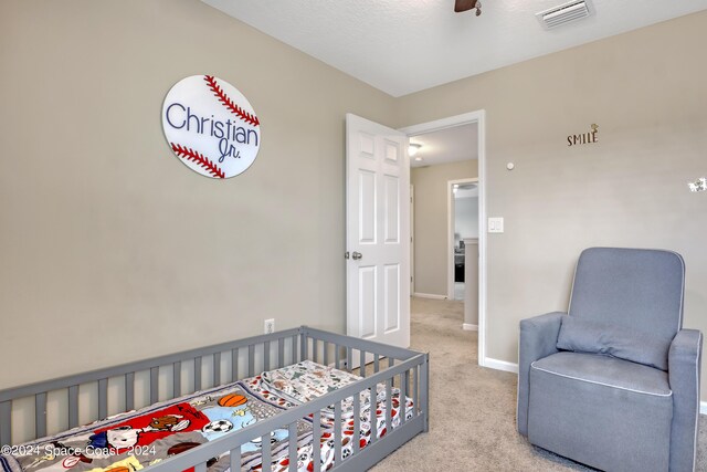 carpeted bedroom with a nursery area and ceiling fan