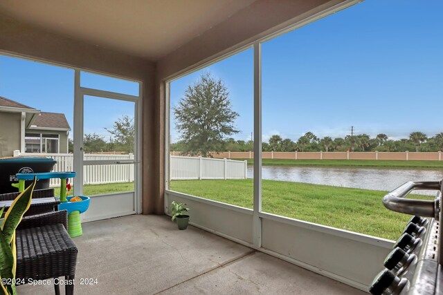 sunroom / solarium with a water view and a healthy amount of sunlight