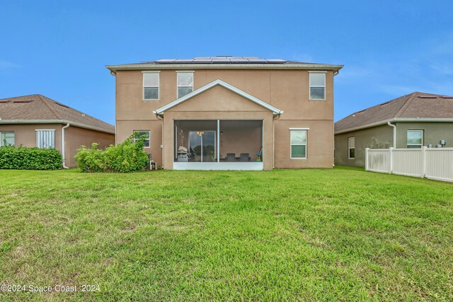 back of property with a sunroom and a lawn