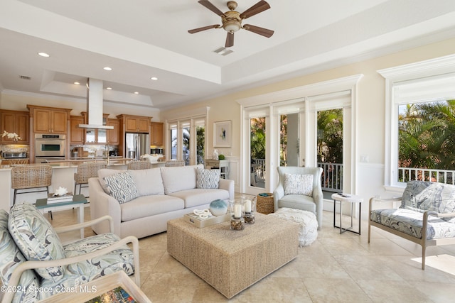 living room with a wealth of natural light, ceiling fan, a tray ceiling, and light tile patterned floors