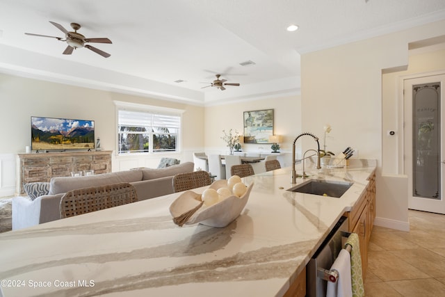 kitchen featuring sink, light stone counters, ornamental molding, ceiling fan, and light tile patterned floors