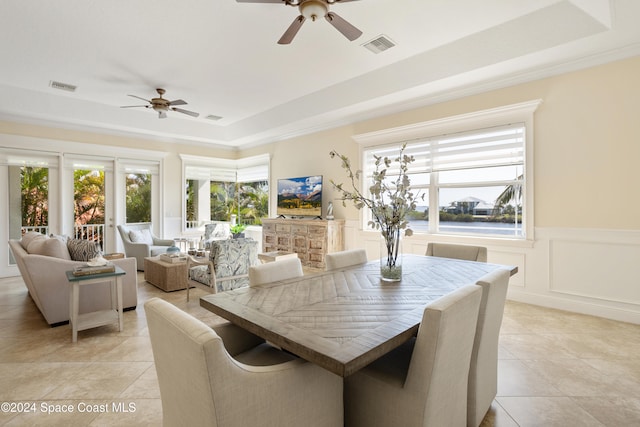 tiled dining space with a healthy amount of sunlight, ceiling fan, and a tray ceiling