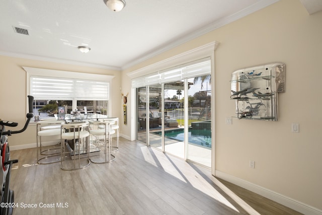 dining area featuring ornamental molding, light hardwood / wood-style floors, and a healthy amount of sunlight