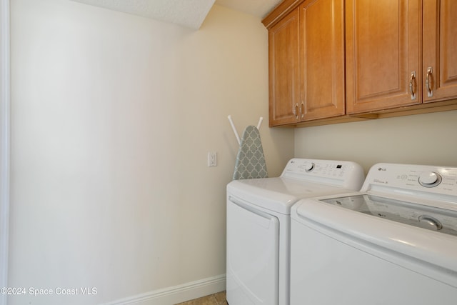 washroom featuring cabinets, a textured ceiling, and washer and clothes dryer