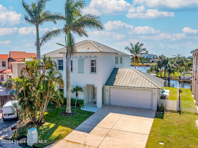 view of front of home with a garage, a water view, and a front lawn