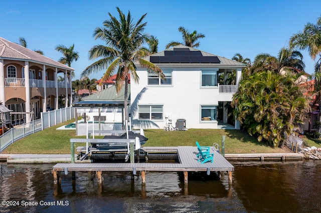 dock area with central air condition unit, a water view, and a yard